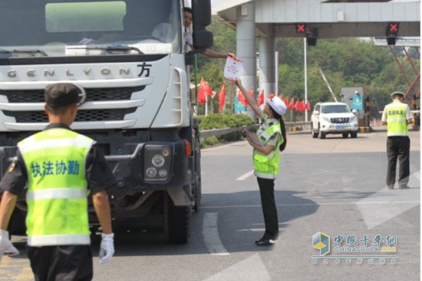 G65巴南收費(fèi)站，交通執(zhí)法人員向接受檢查的貨車駕駛員發(fā)放安全出現(xiàn)宣傳頁